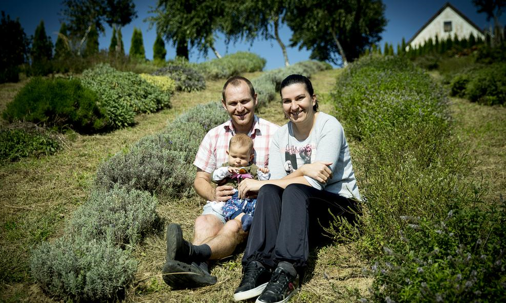 Špela in Boris s sinčkom Florjanom v zeliščnem nasadu na domači kmetiji.